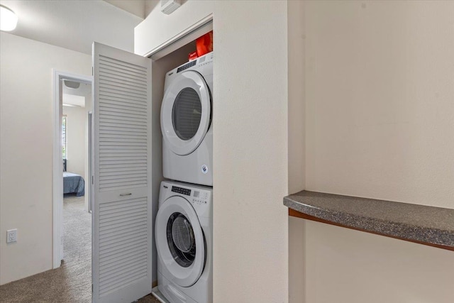 clothes washing area featuring carpet floors and stacked washing maching and dryer