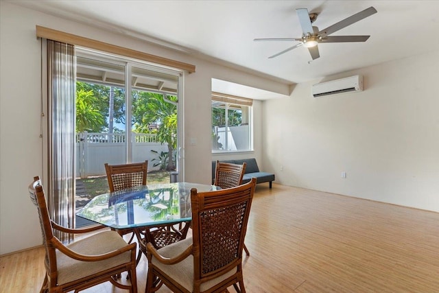 dining room featuring light wood-type flooring, a wall unit AC, and ceiling fan