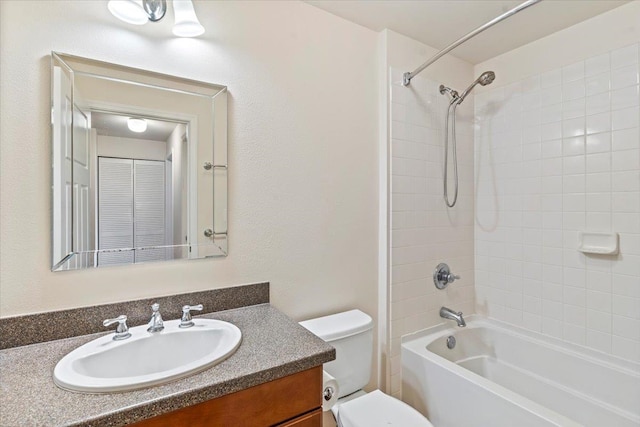 full bathroom with tiled shower / bath, vanity, and toilet