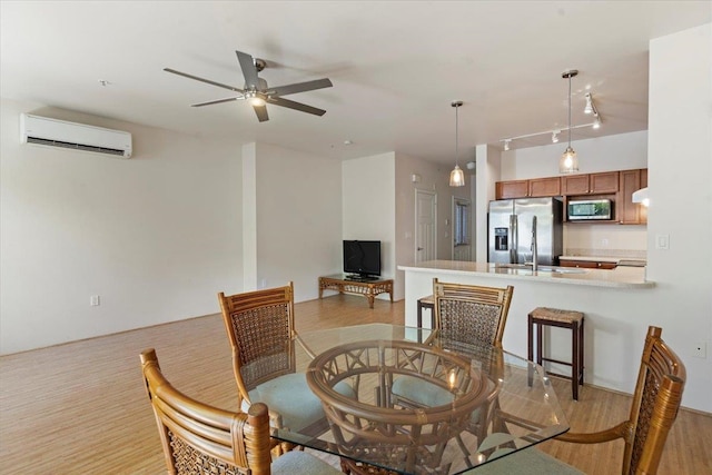 dining area featuring ceiling fan, light wood-type flooring, rail lighting, and an AC wall unit