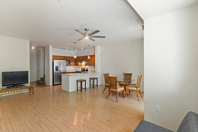 living room with light hardwood / wood-style flooring, ceiling fan, and sink