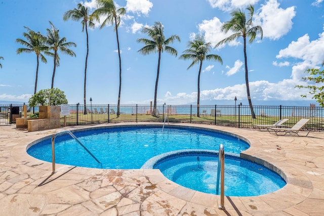 view of swimming pool featuring an in ground hot tub, a water view, and a patio