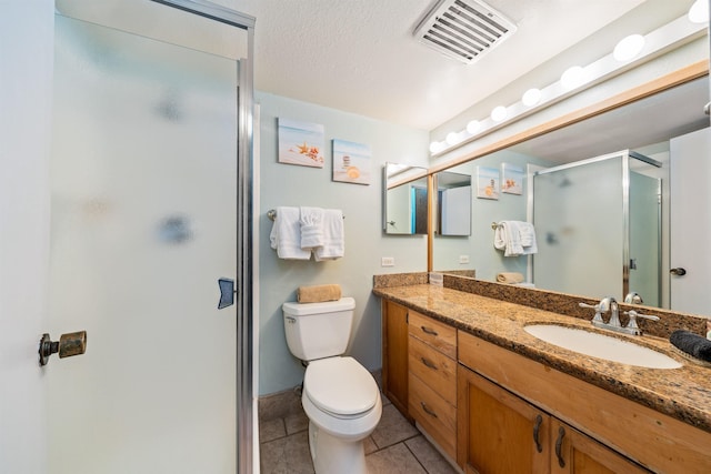 bathroom featuring tile patterned floors, vanity, a shower with shower door, and toilet