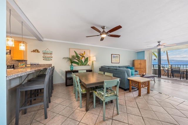 tiled dining room with a water view, ceiling fan, and ornamental molding