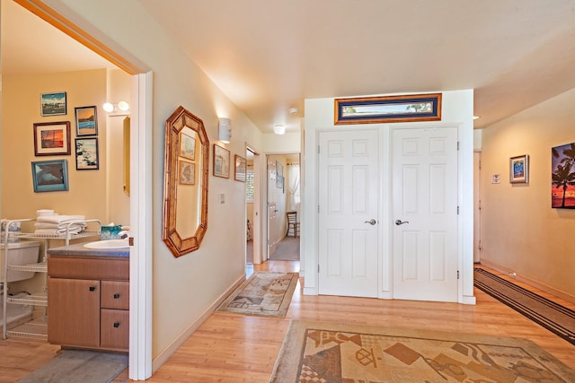 hallway with baseboard heating, sink, and light hardwood / wood-style floors