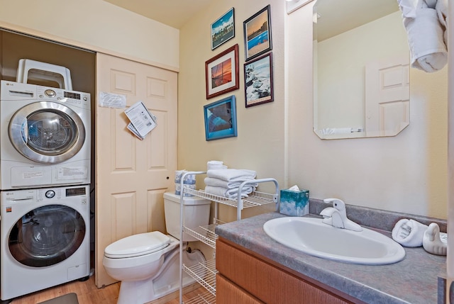 bathroom with vanity, hardwood / wood-style flooring, stacked washer and clothes dryer, and toilet