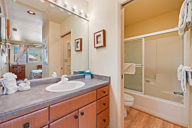 full bathroom featuring vanity, hardwood / wood-style floors, shower / bath combination with glass door, and toilet