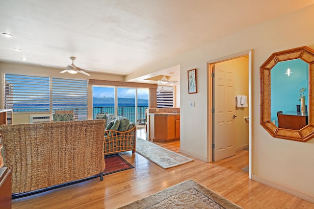 living room featuring hardwood / wood-style flooring, a water view, and ceiling fan