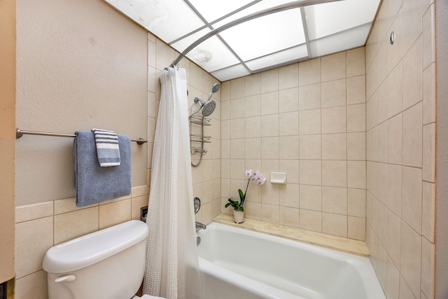 bathroom featuring tile walls, shower / bath combination with curtain, and toilet