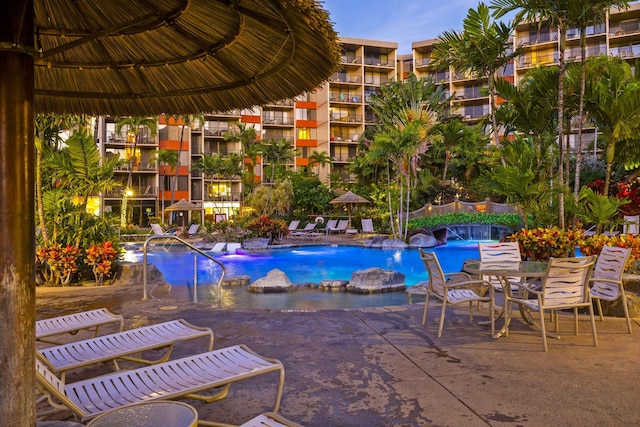 pool at dusk featuring a patio and pool water feature