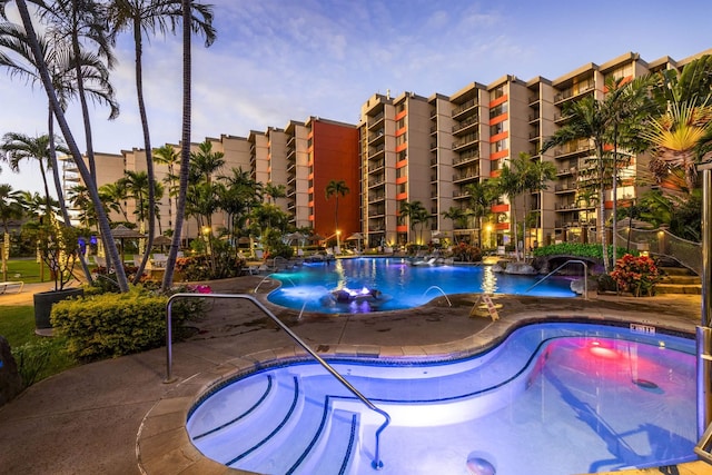 pool at dusk featuring pool water feature and a patio area