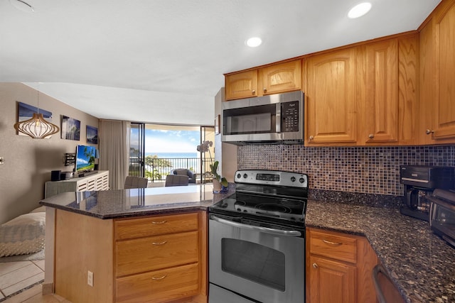 kitchen with stainless steel appliances, kitchen peninsula, dark stone counters, and backsplash