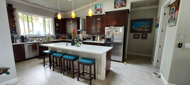 kitchen featuring pendant lighting, a breakfast bar, wall chimney range hood, a kitchen island, and stainless steel appliances