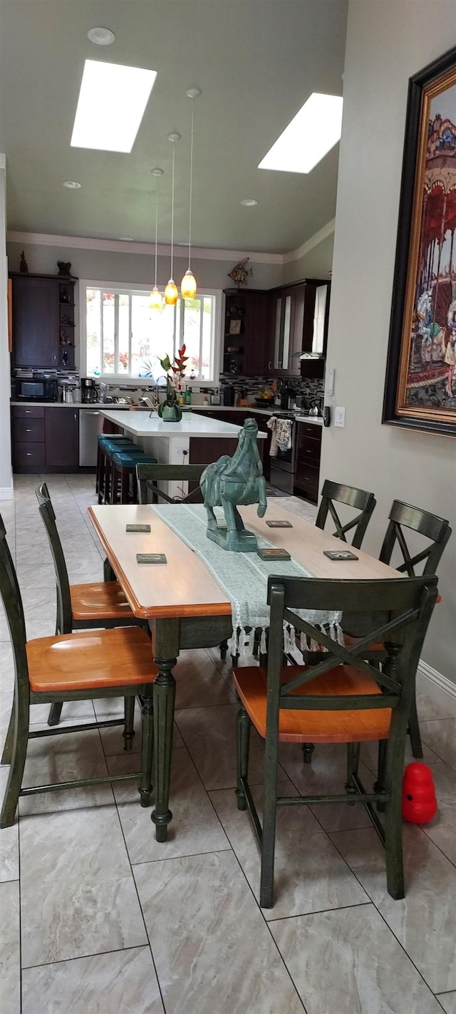 dining area with ornamental molding and a skylight