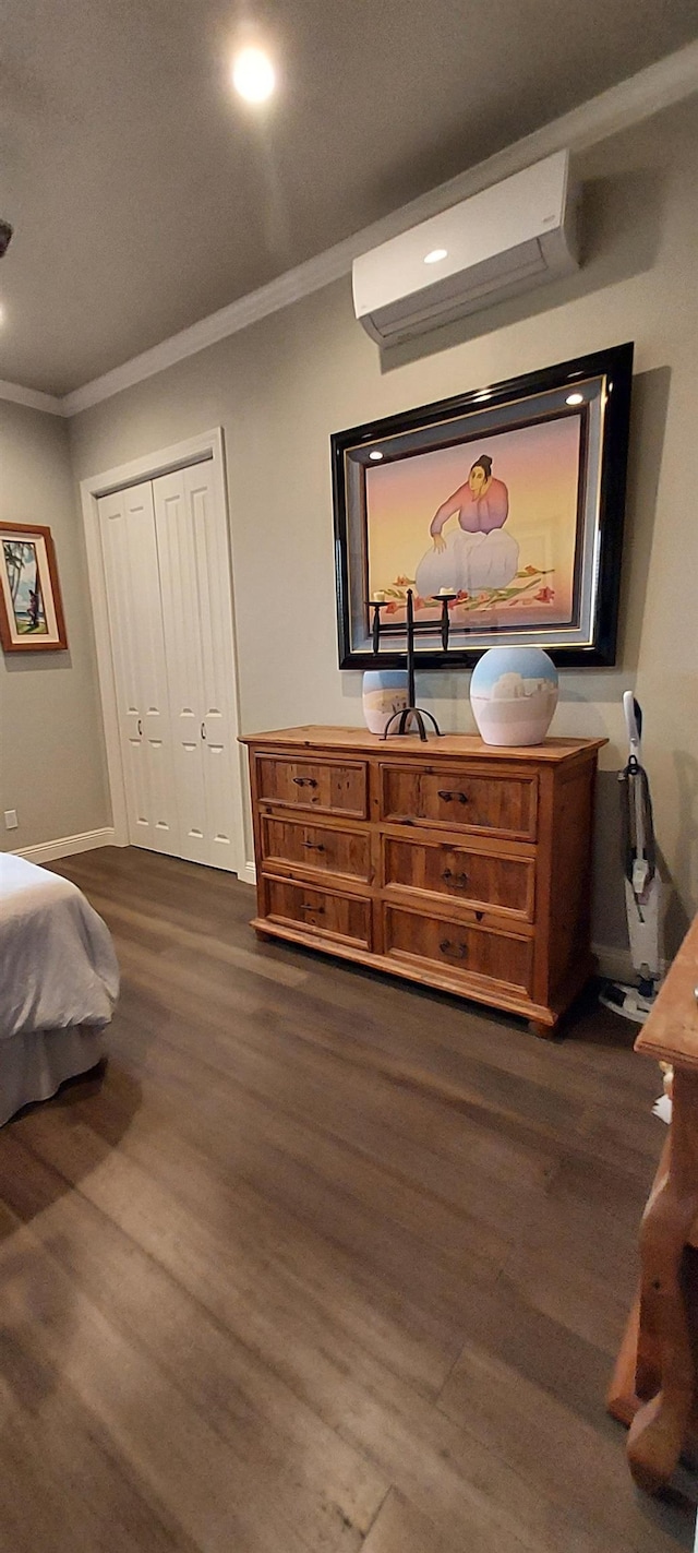 bedroom with an AC wall unit, a closet, dark hardwood / wood-style flooring, and ornamental molding