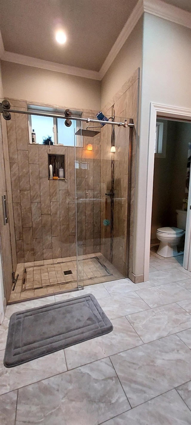 bathroom featuring toilet, a shower with door, and crown molding