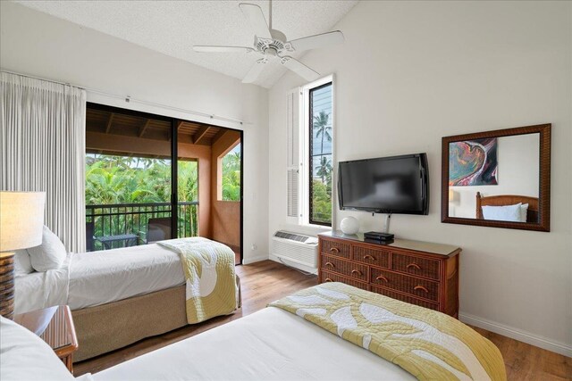 3300 Wailea Alanui St Unit 3A, Kihei, HI 96753 - bedroom featuring access to exterior, an AC wall unit, wood finished floors, baseboards, and lofted ceiling