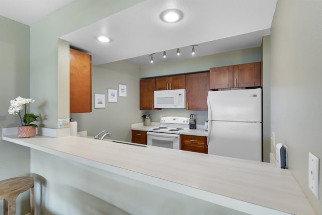 kitchen featuring kitchen peninsula, white appliances, a breakfast bar area, and sink