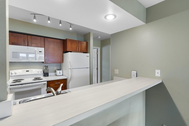 kitchen featuring kitchen peninsula, sink, and white appliances