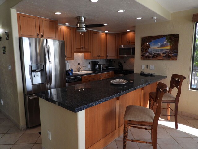 kitchen with stainless steel appliances, ceiling fan, tasteful backsplash, and light tile flooring