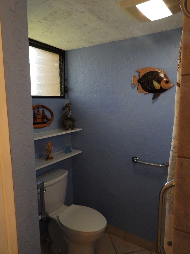 bathroom with tile flooring, a textured ceiling, and toilet