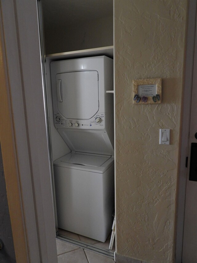 washroom featuring stacked washer / dryer and light tile floors