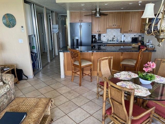 kitchen featuring hanging light fixtures, kitchen peninsula, stainless steel refrigerator with ice dispenser, ceiling fan, and light tile floors