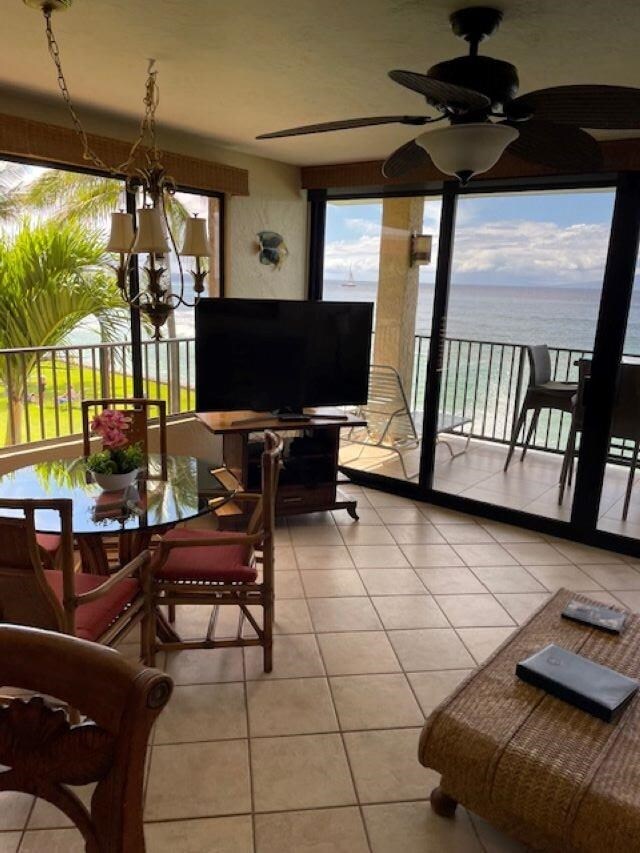 tiled living room with ceiling fan and a water view