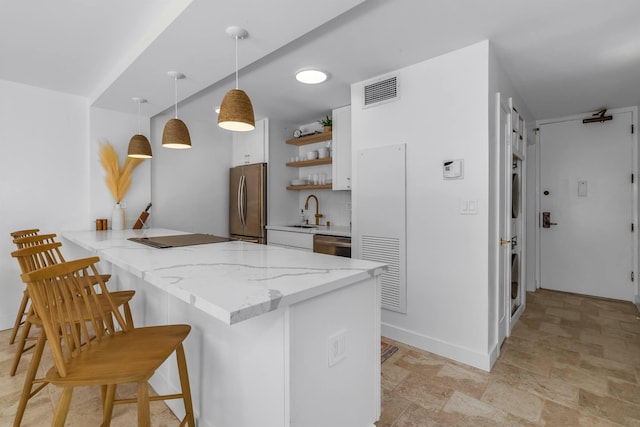 kitchen with hanging light fixtures, kitchen peninsula, a kitchen bar, white cabinets, and appliances with stainless steel finishes