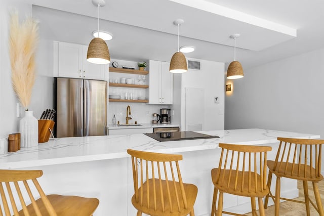 kitchen featuring white cabinetry, kitchen peninsula, and stainless steel refrigerator