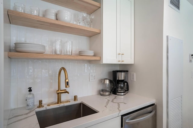 kitchen with sink, stainless steel dishwasher, light stone countertops, tasteful backsplash, and white cabinetry