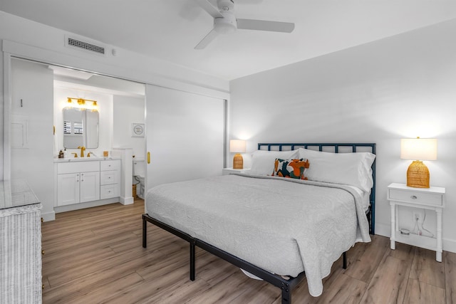 bedroom featuring connected bathroom, ceiling fan, light hardwood / wood-style flooring, and sink