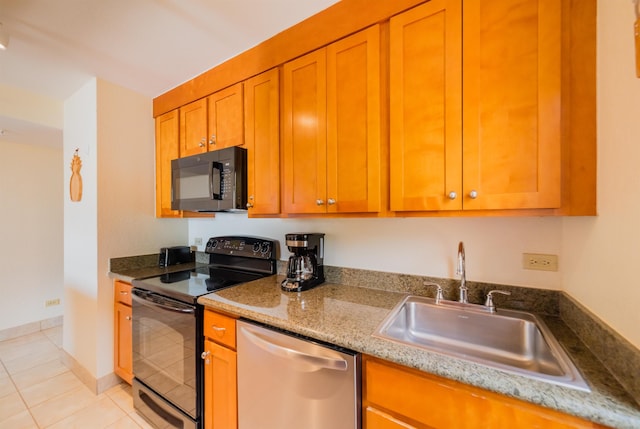 kitchen featuring brown cabinets, a sink, black appliances, light tile patterned flooring, and light stone countertops