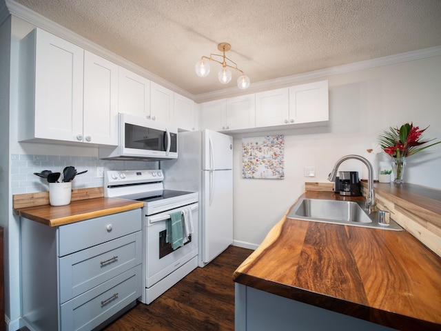 kitchen with white appliances, dark wood-type flooring, sink, butcher block countertops, and white cabinetry