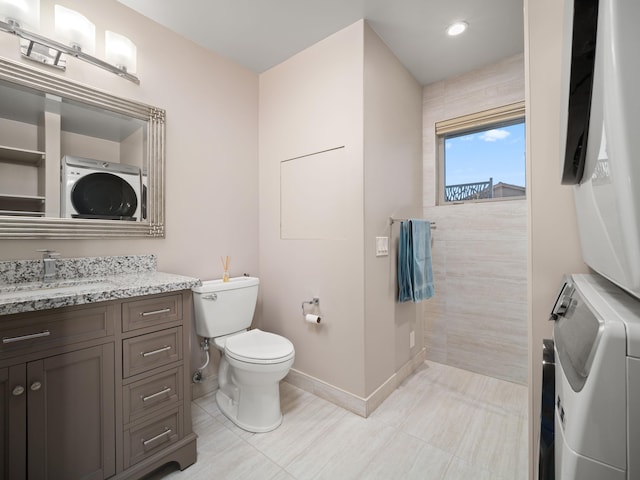 bathroom with estacked washer and dryer, toilet, baseboards, vanity, and recessed lighting