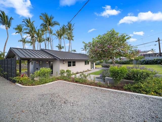 view of front of property with a standing seam roof, metal roof, stucco siding, and fence