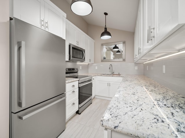 kitchen with stainless steel appliances, a sink, tasteful backsplash, vaulted ceiling, and white cabinetry