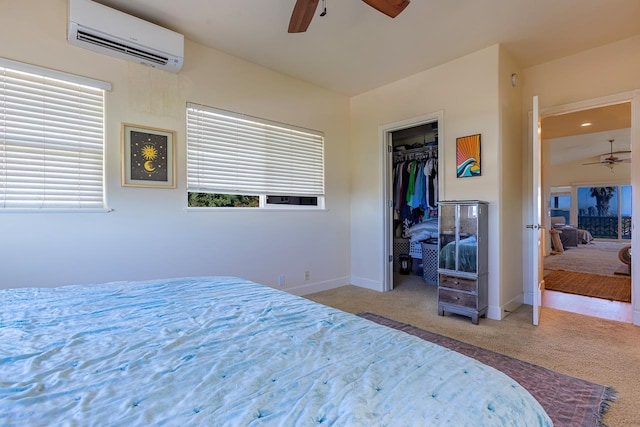 carpeted bedroom featuring a wall mounted AC, ceiling fan, a walk in closet, and a closet