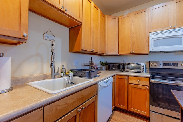 kitchen featuring light wood-type flooring, white appliances, and sink