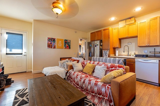 living room with light hardwood / wood-style flooring, ceiling fan, and sink