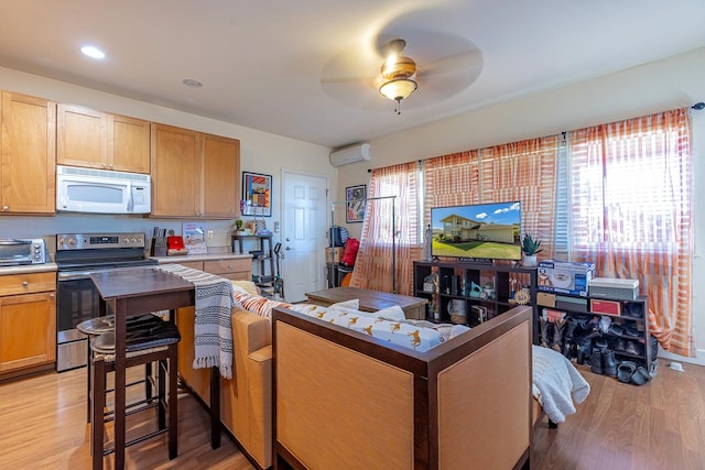 kitchen featuring light wood-type flooring, stainless steel range with electric cooktop, an AC wall unit, and ceiling fan