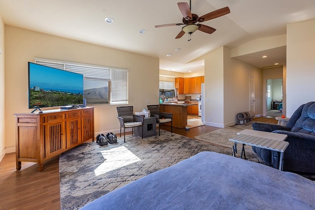 living room with ceiling fan, vaulted ceiling, and dark hardwood / wood-style flooring