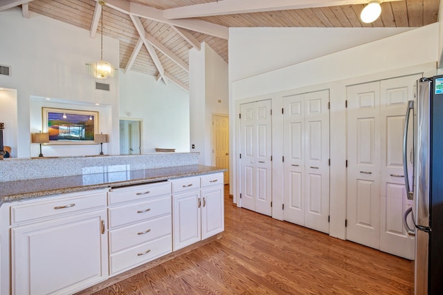 kitchen with white cabinetry, high vaulted ceiling, stainless steel refrigerator, and decorative light fixtures