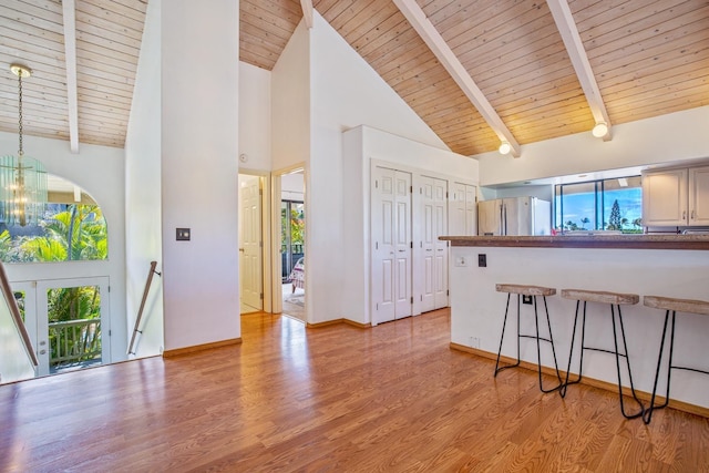 kitchen featuring light wood-type flooring, stainless steel fridge, wooden ceiling, beam ceiling, and high vaulted ceiling