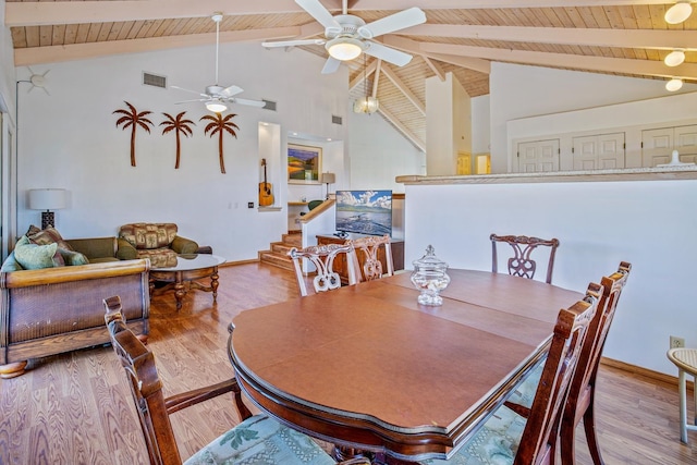 dining room featuring beam ceiling, light hardwood / wood-style flooring, and high vaulted ceiling