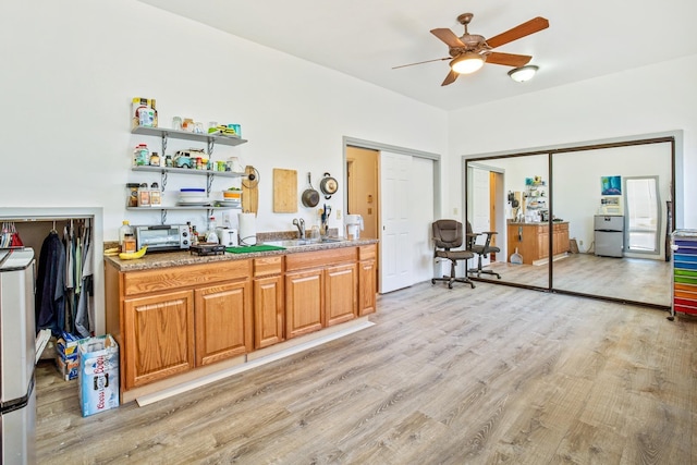 bar featuring sink, ceiling fan, and light hardwood / wood-style flooring