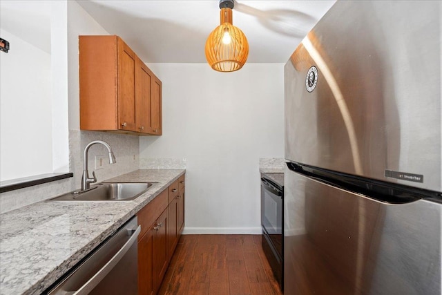 kitchen with dark wood finished floors, brown cabinetry, appliances with stainless steel finishes, light countertops, and a sink