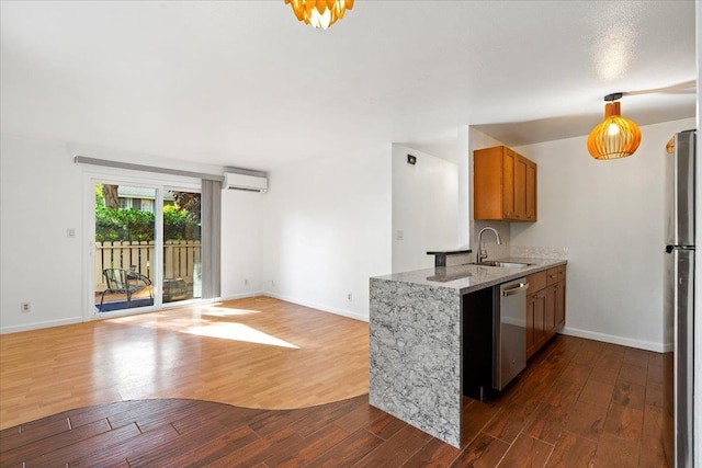 kitchen featuring appliances with stainless steel finishes, brown cabinets, dark wood-type flooring, a wall mounted air conditioner, and a sink