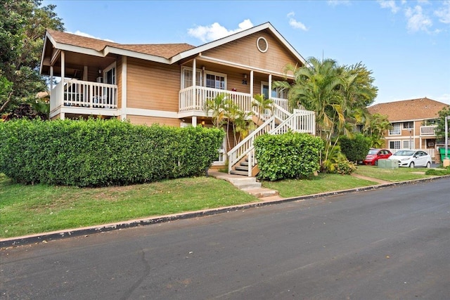 view of front of house featuring a porch, stairway, and a front lawn