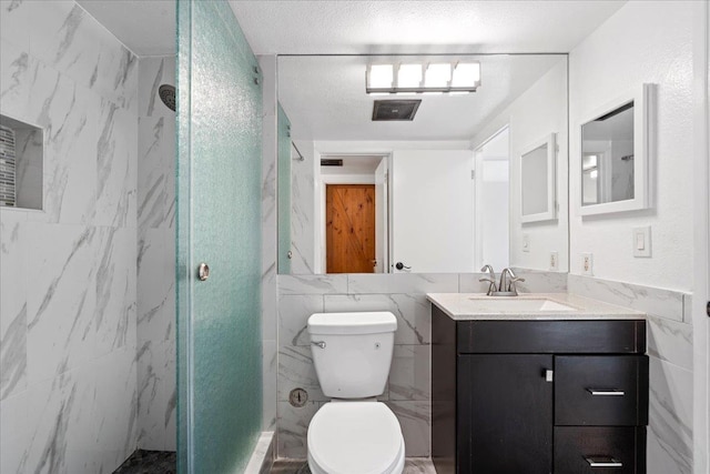 bathroom with toilet, vanity, a marble finish shower, and tile walls